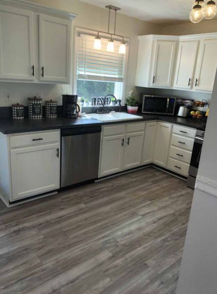 A kitchen with white cabinets and a stainless steel dishwasher