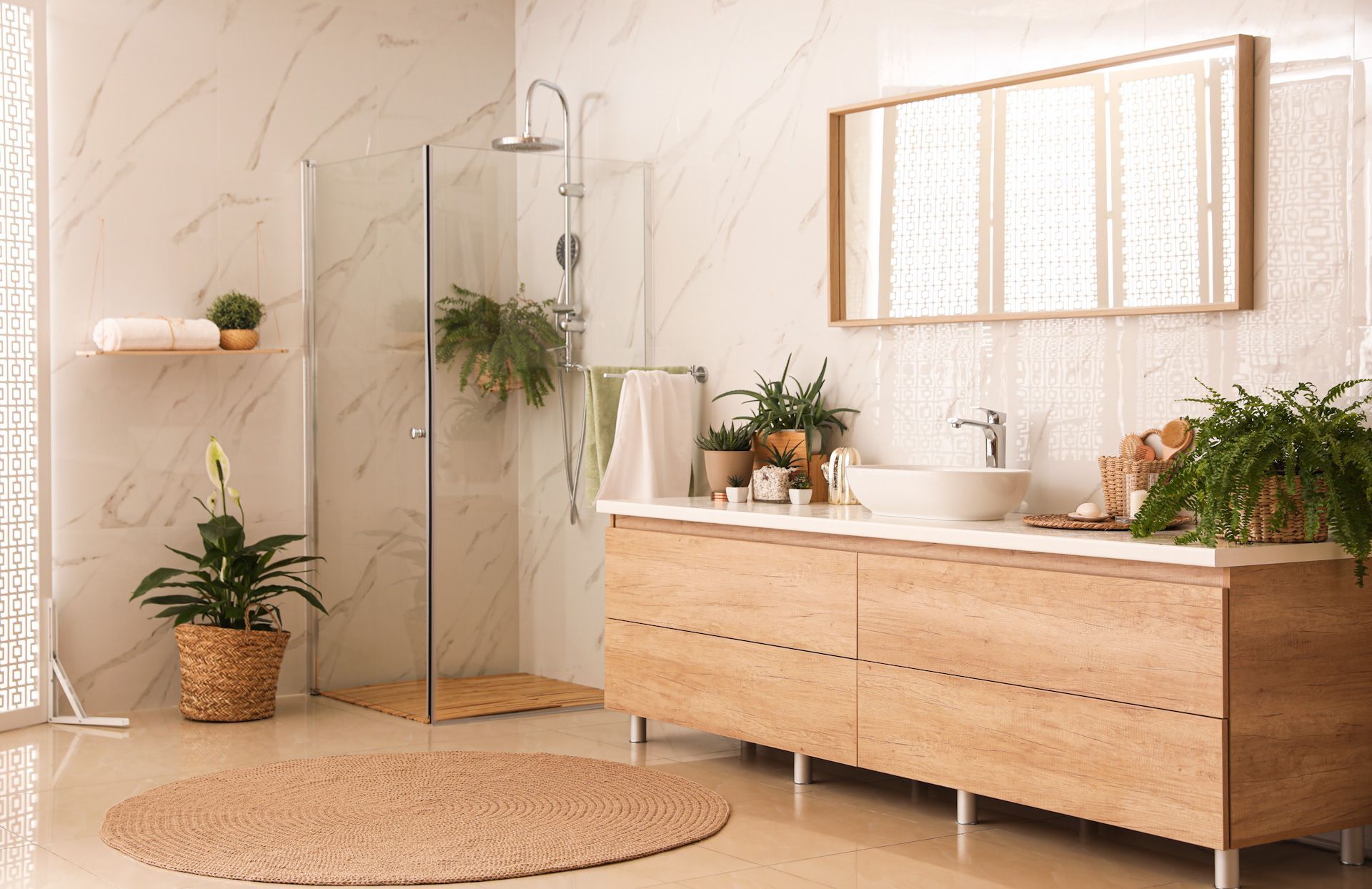 A bathroom with a walk in shower, sink, mirror and plants.