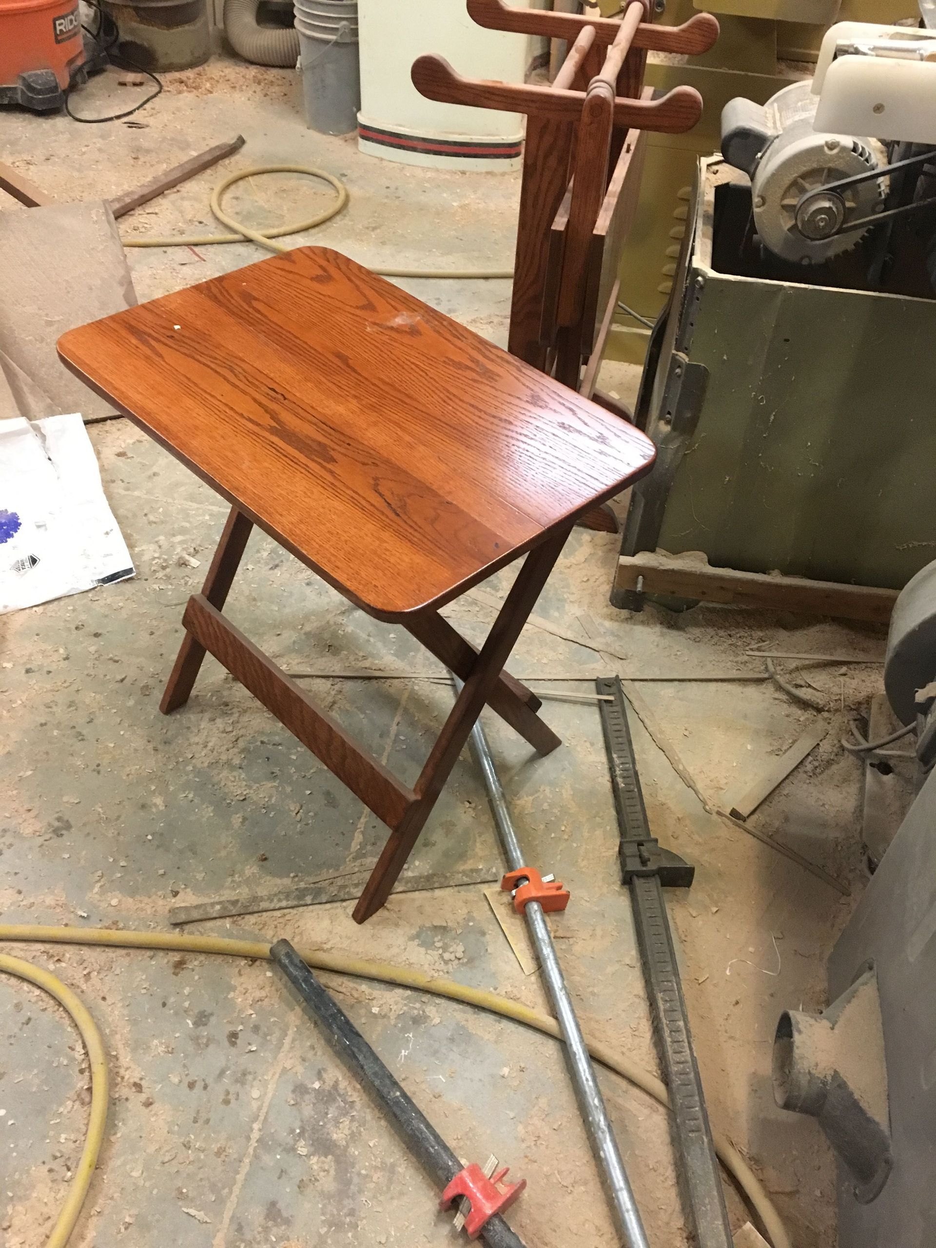 A small wooden table is sitting on the floor in a workshop.