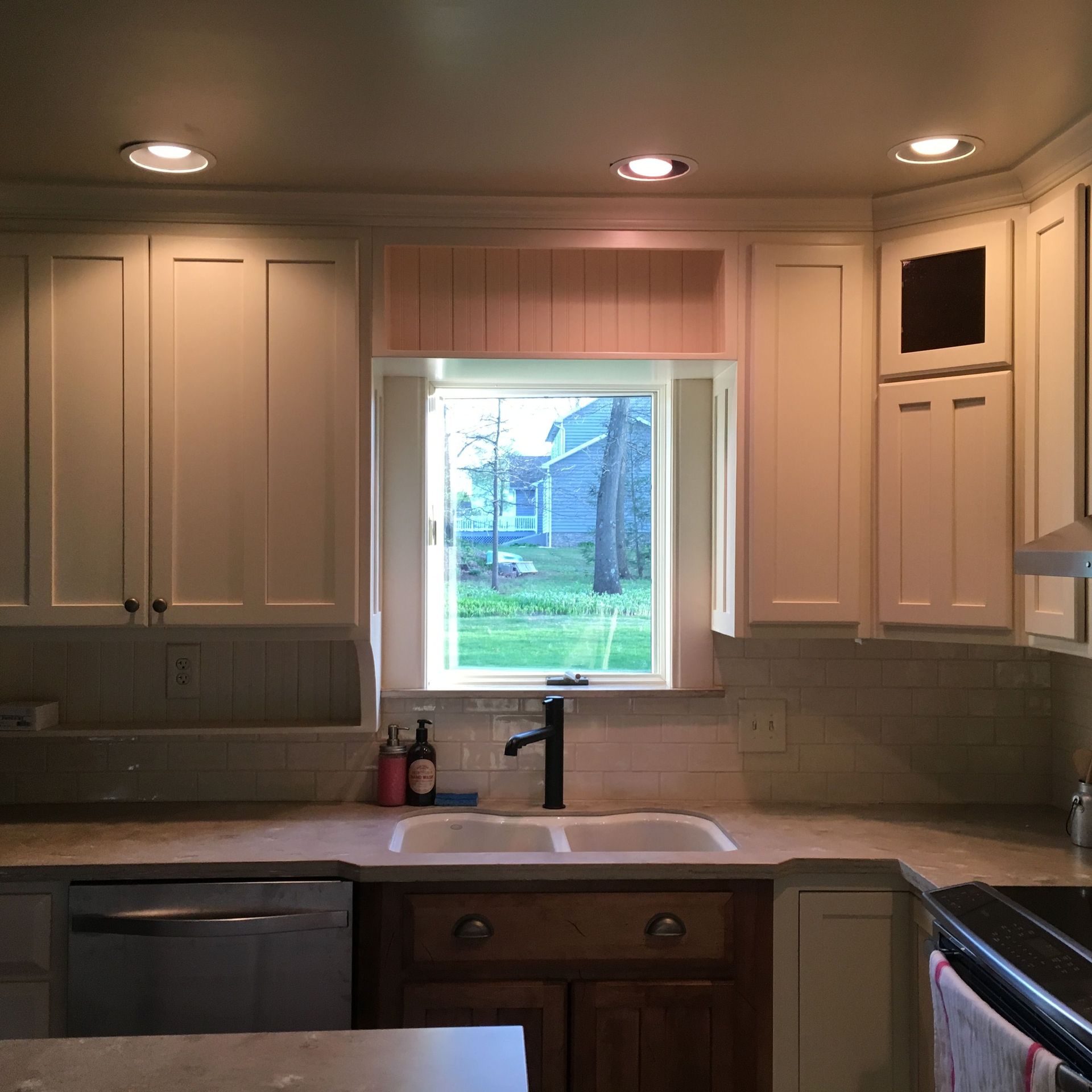 A kitchen with white cabinets and a window over the sink