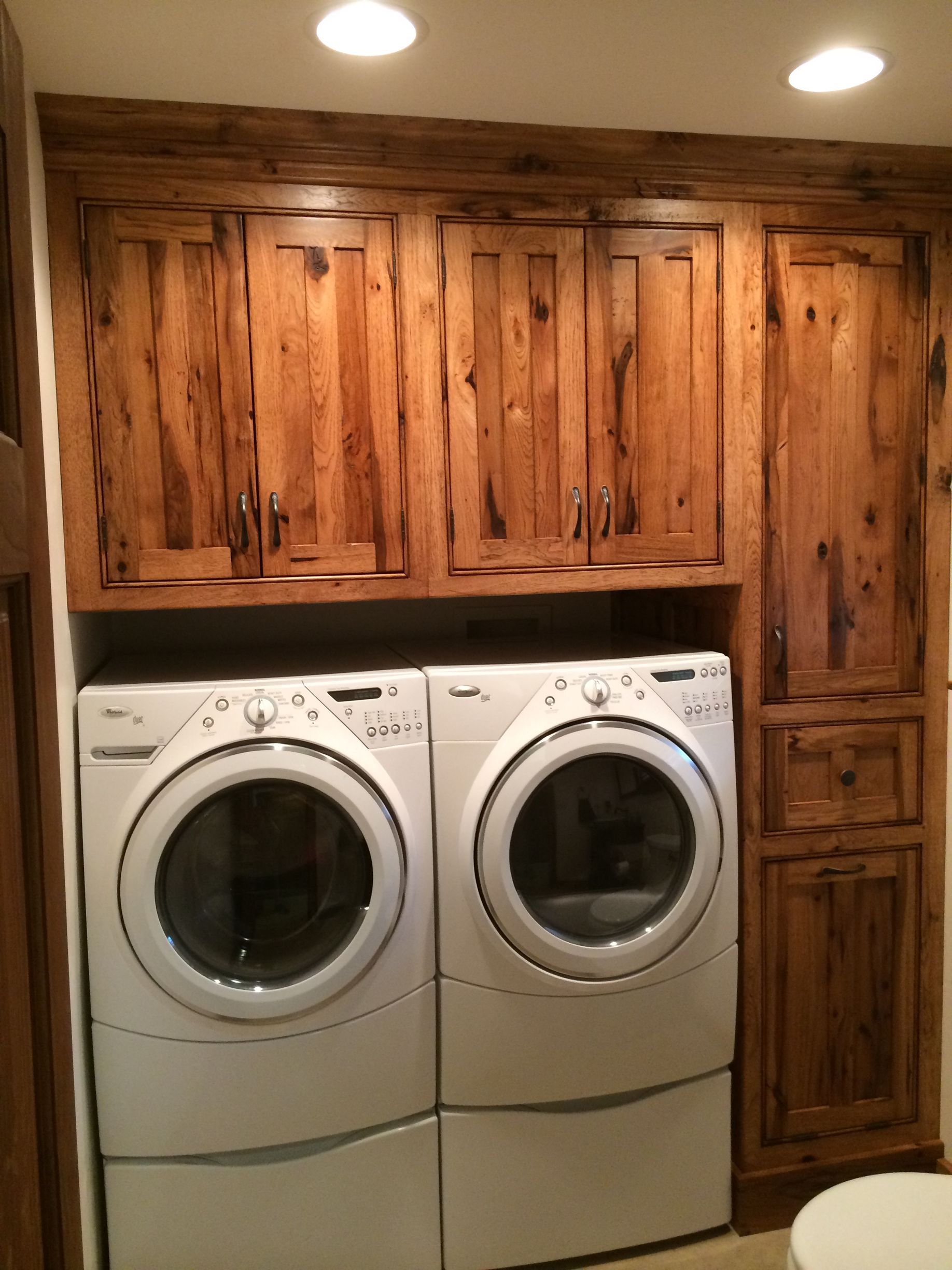 A washer and dryer in a laundry room with wooden cabinets