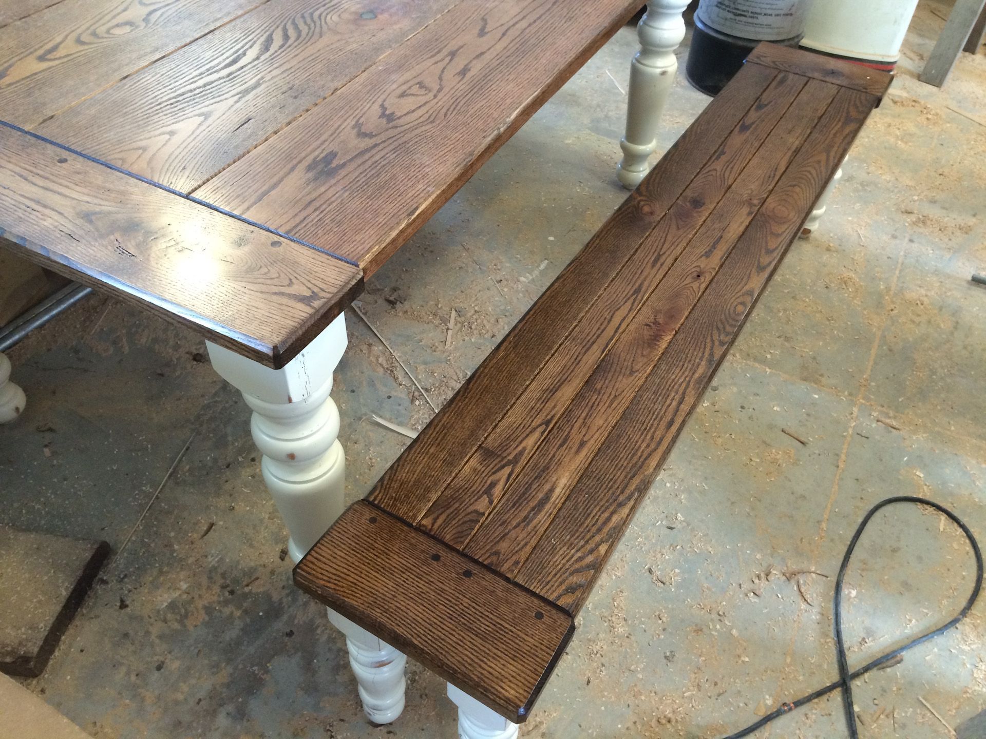 A wooden bench is sitting next to a wooden table.