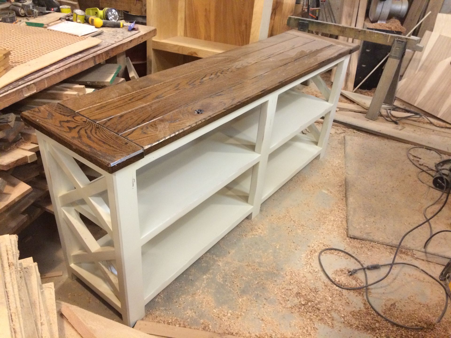 A wooden table with three shelves is being built in a workshop.