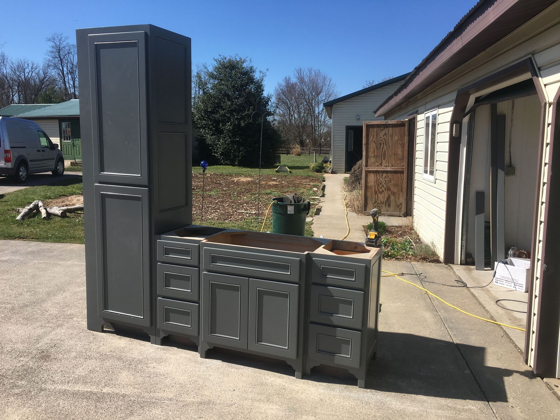 A bunch of cabinets are sitting in a driveway in front of a house