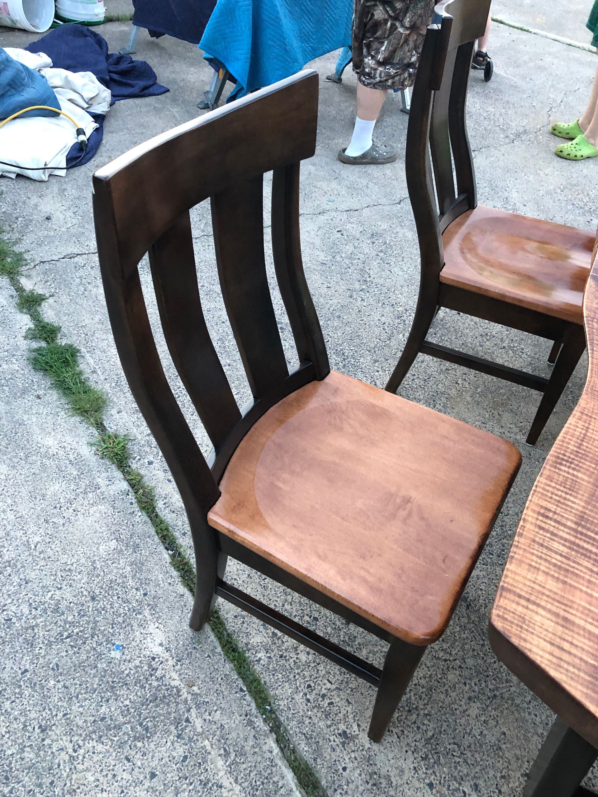 A wooden chair is sitting on the sidewalk next to a table.