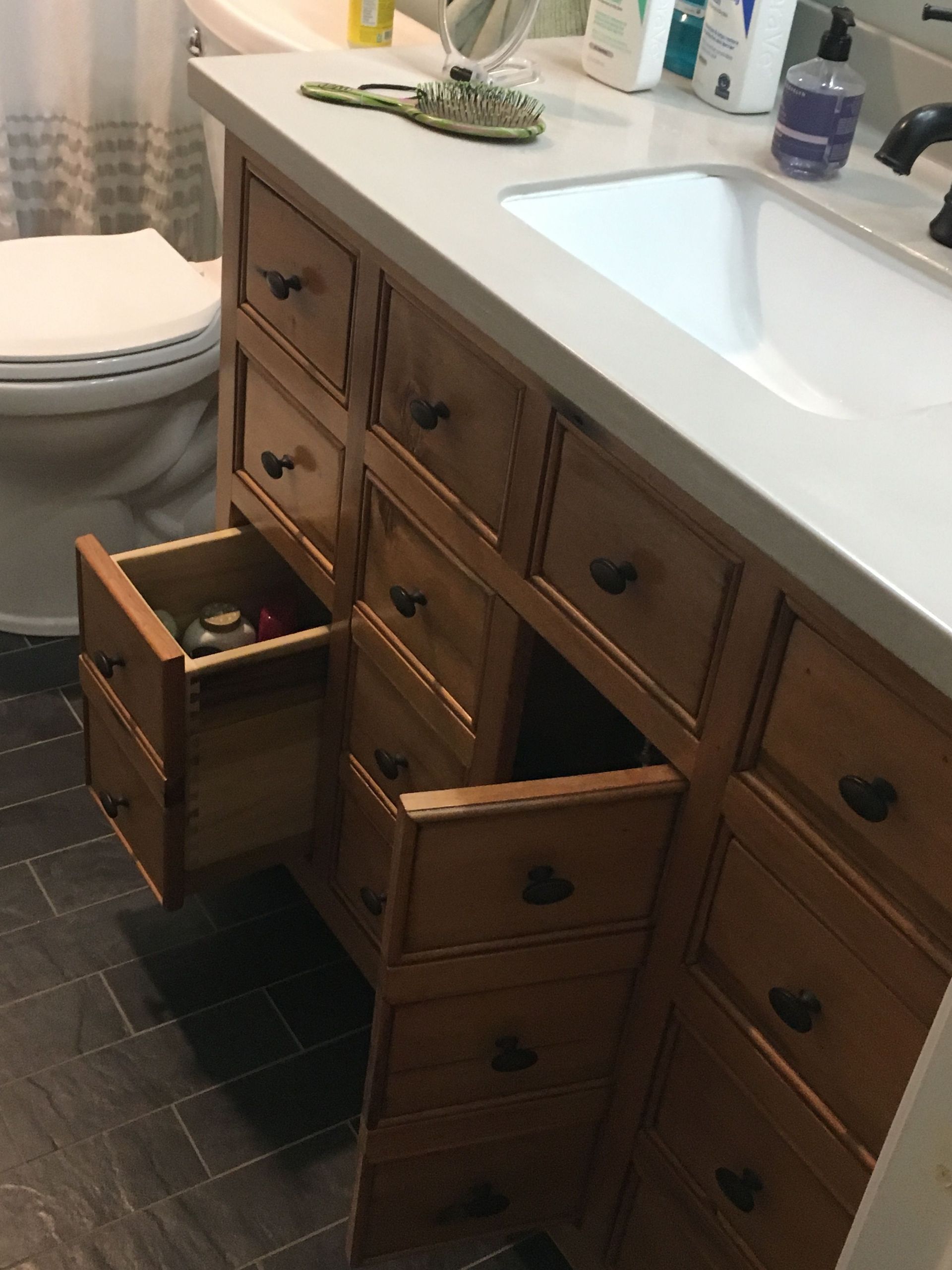 A bathroom vanity with drawers open and a toilet