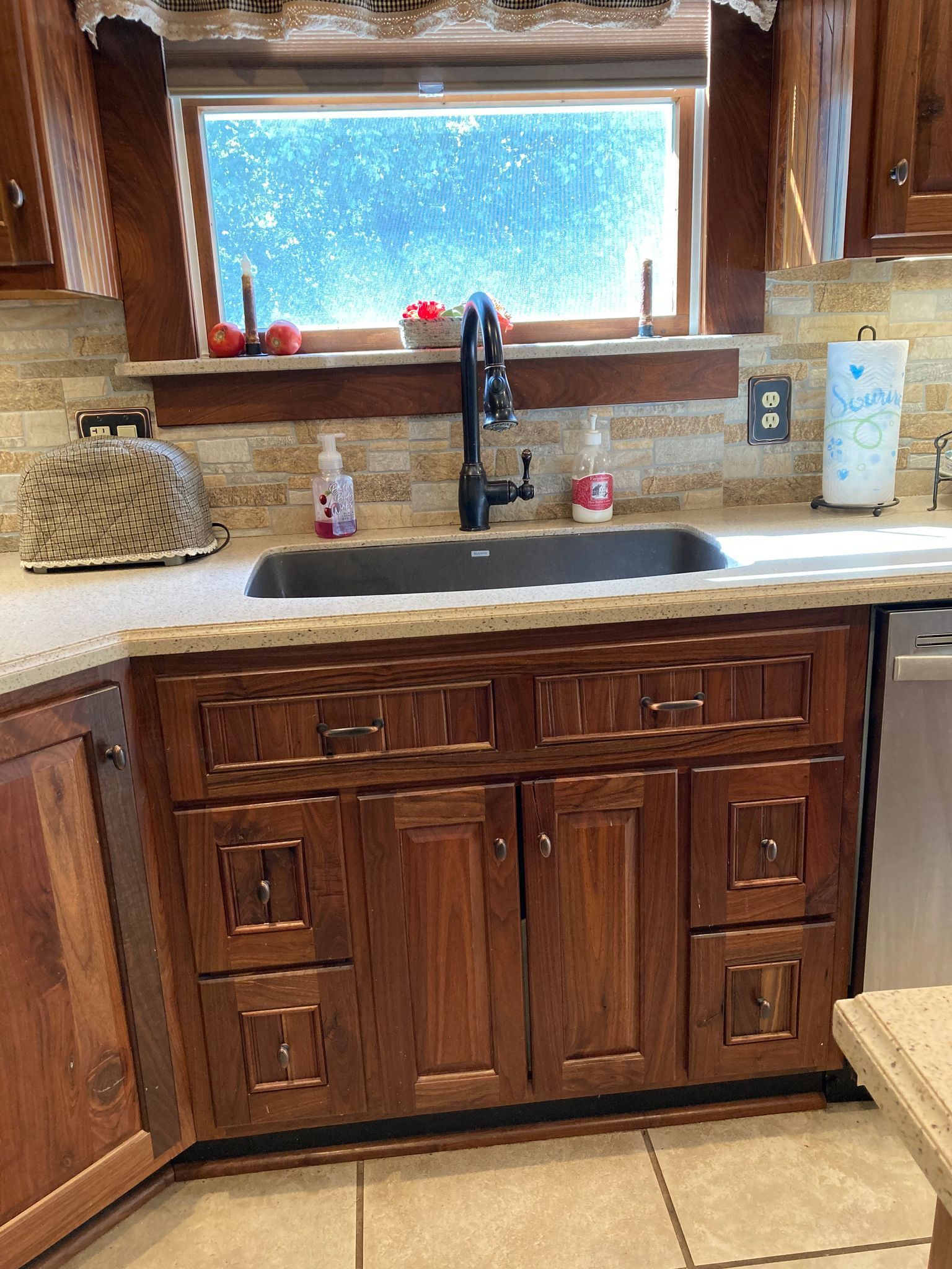A kitchen with wooden cabinets, a sink, and a window.