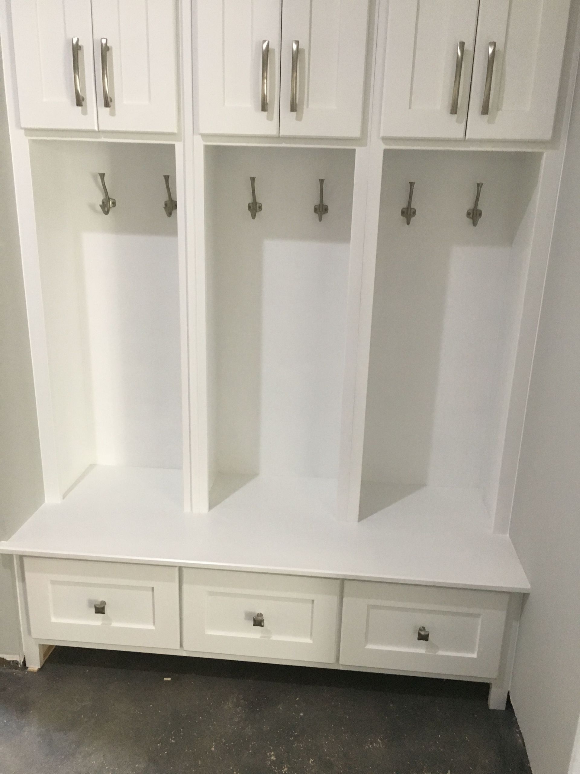 A white cabinet with drawers and hooks in a room.