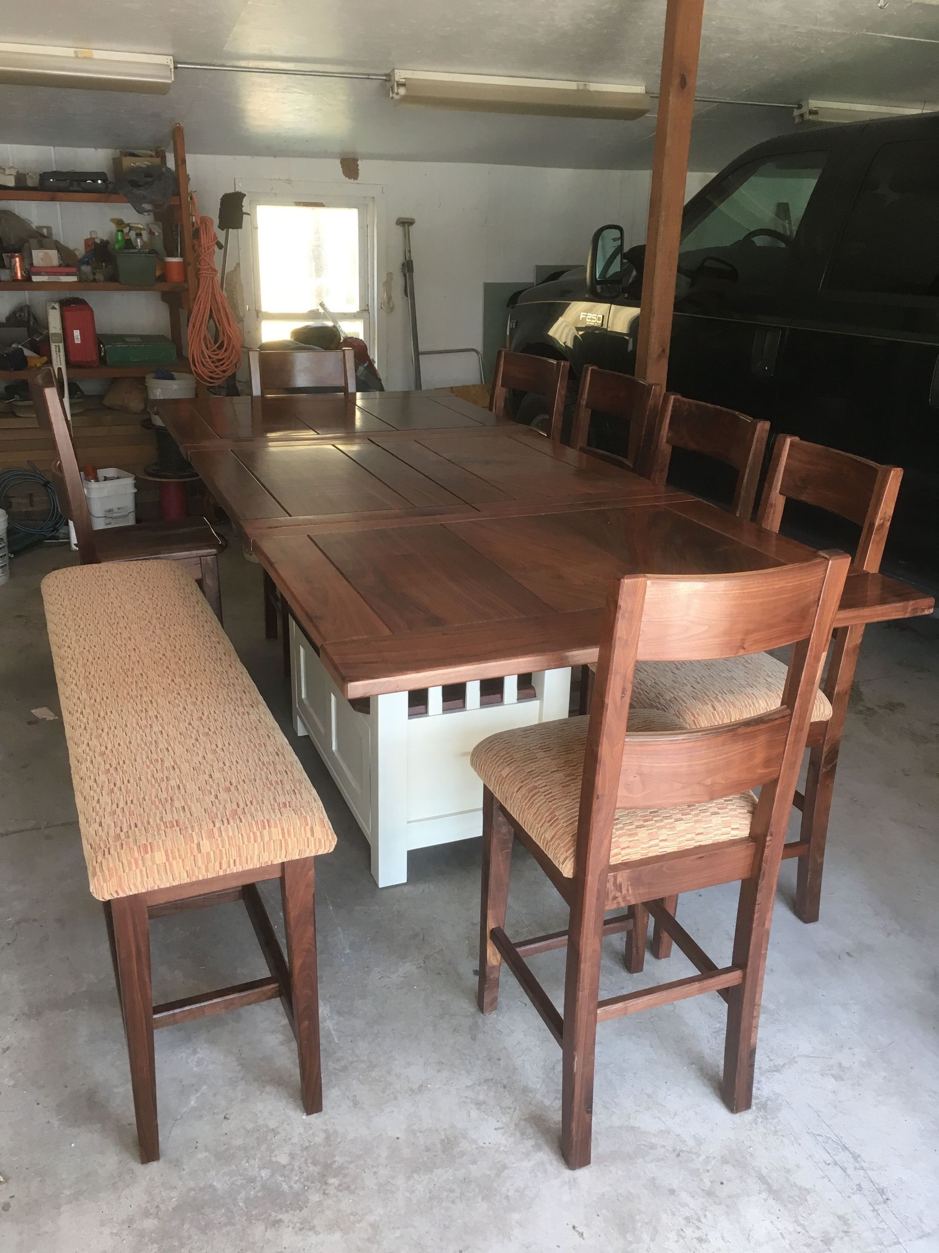 A wooden table with chairs and a bench in a garage.