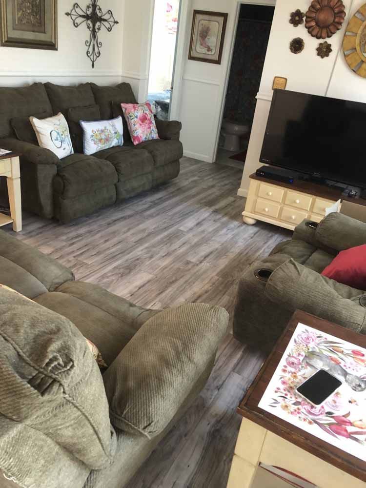 A living room with a couch , chairs , and a flat screen tv.