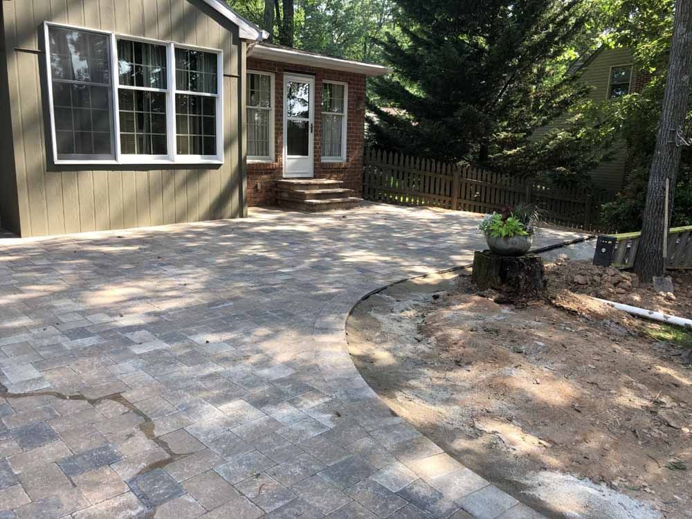 A house with a brick driveway and a wheelbarrow in front of it.