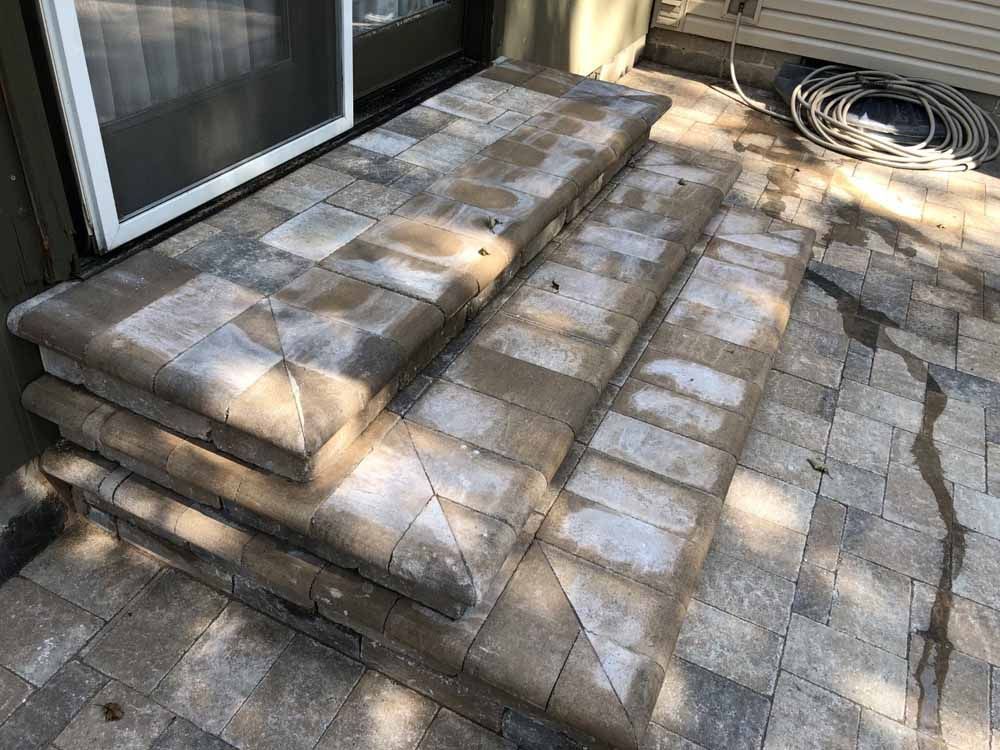 A stack of brick steps leading up to a sliding glass door.