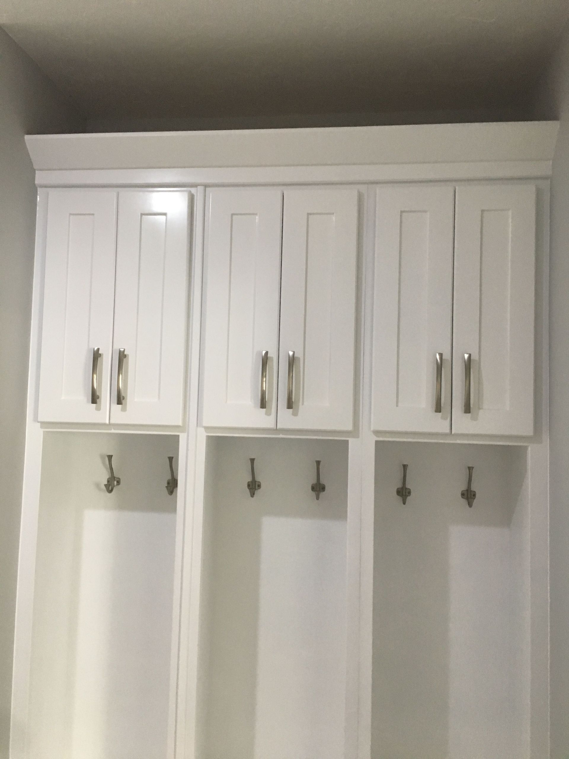 A room with white cabinets and hooks on the wall.