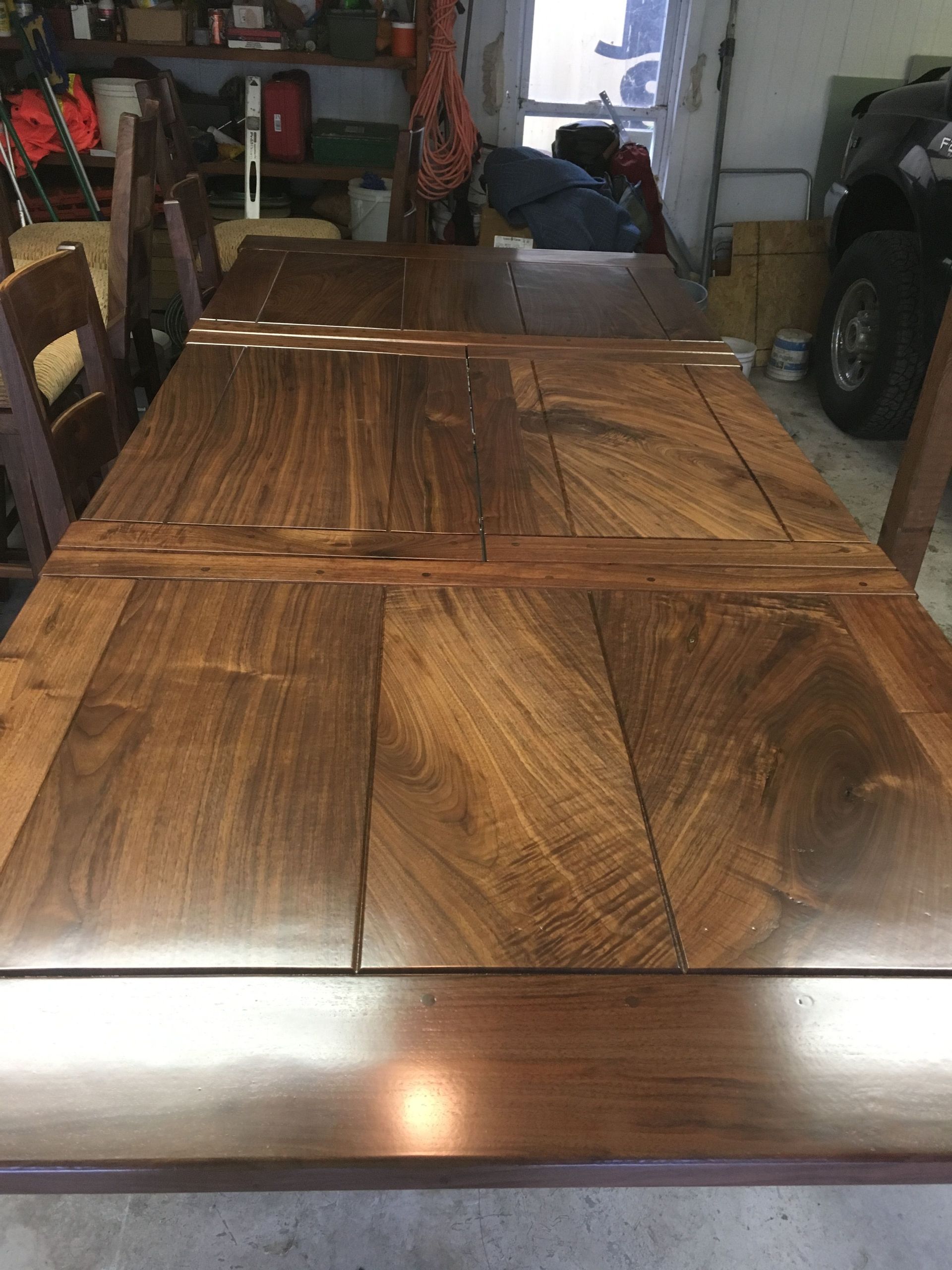 A wooden table is sitting in a garage next to a car.