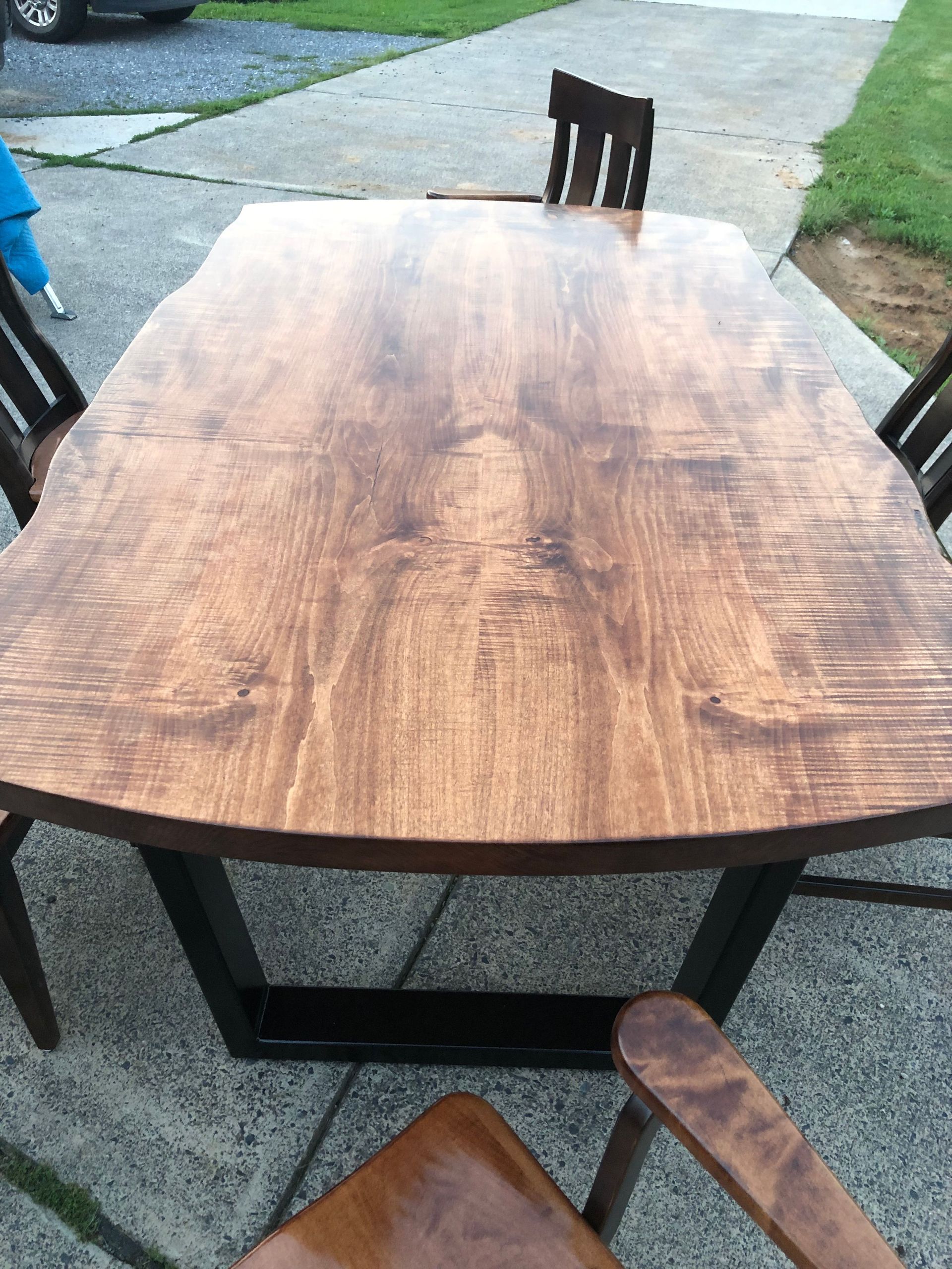 A wooden table and chairs are sitting on a sidewalk.