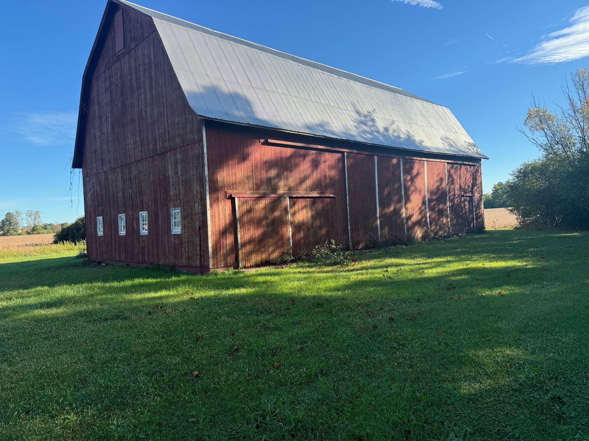 A red barn is sitting in the middle of a grassy field.