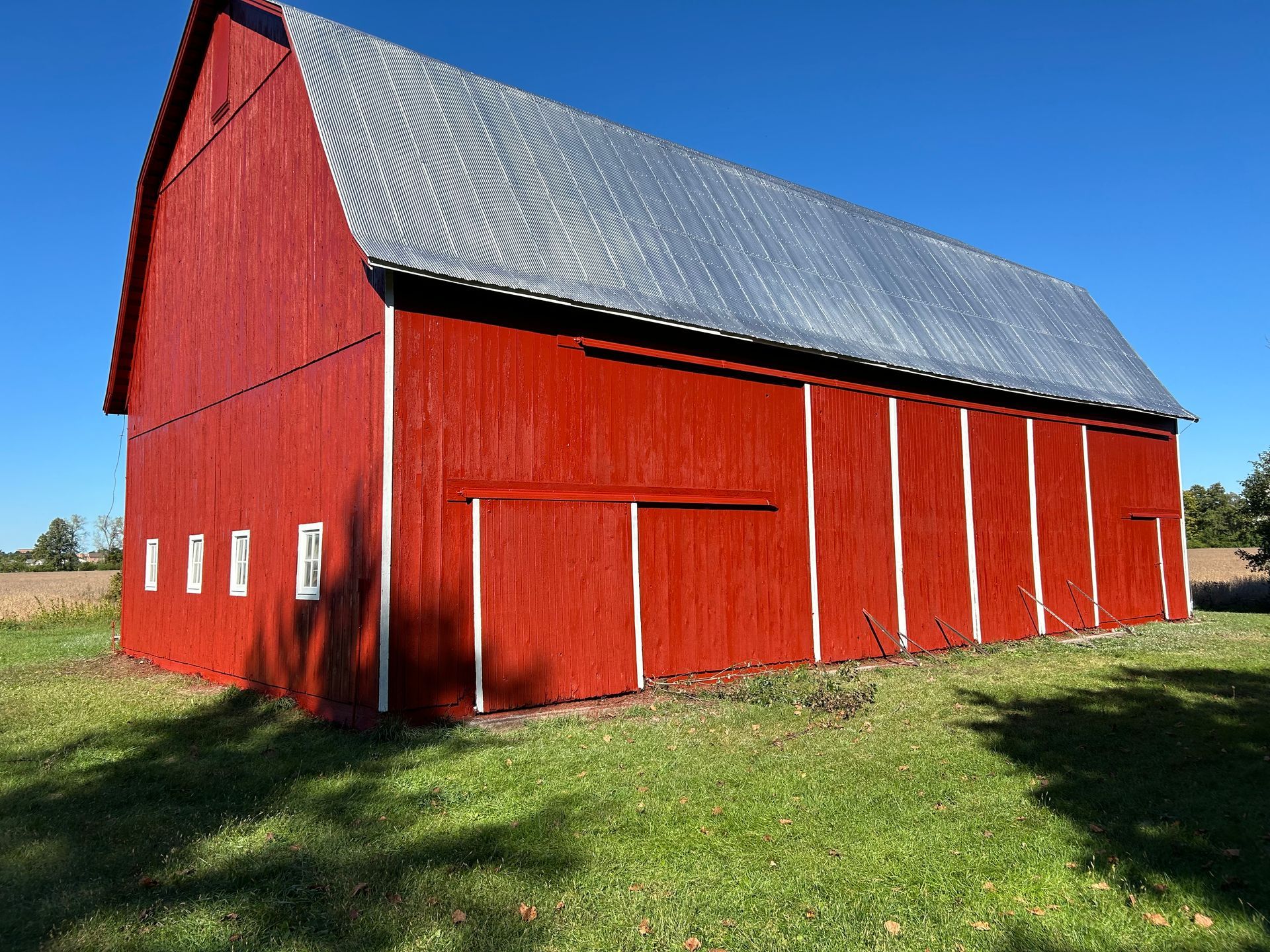 A large red barn is sitting in the middle of a grassy field.