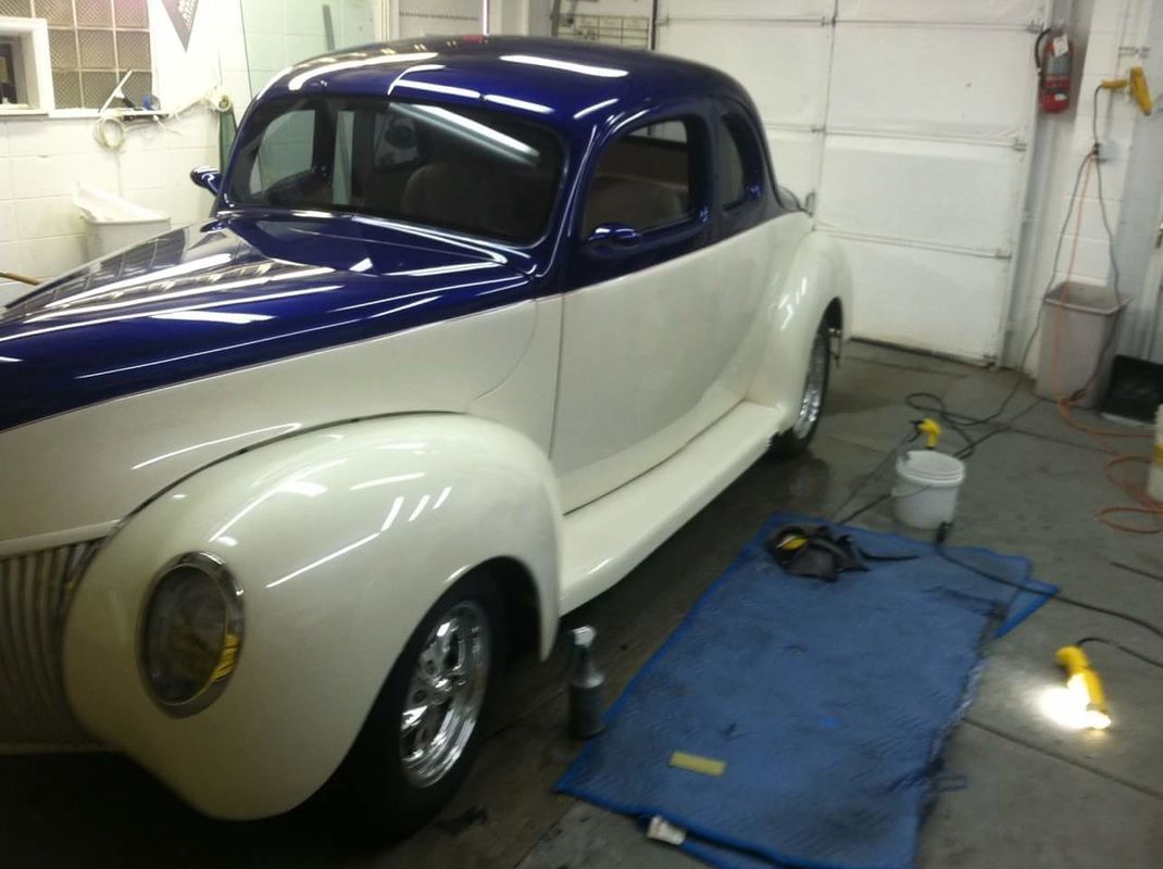 A blue and white car is parked in a garage