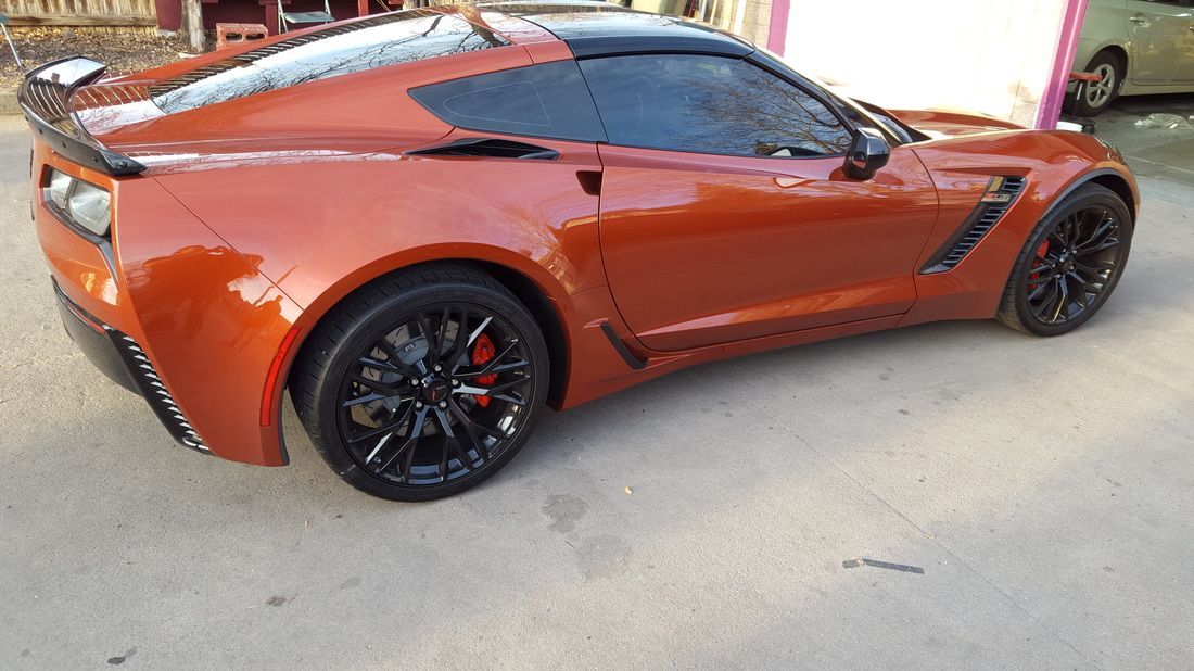 A red sports car with black wheels is parked on the side of the road.
