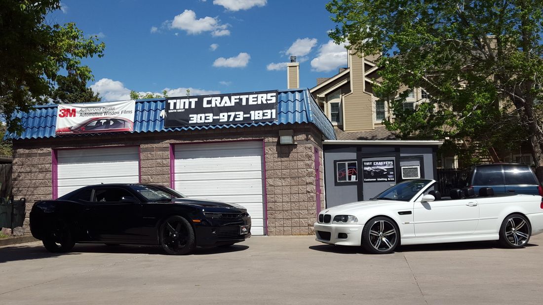 Two cars are parked in front of a building that says tint drafters