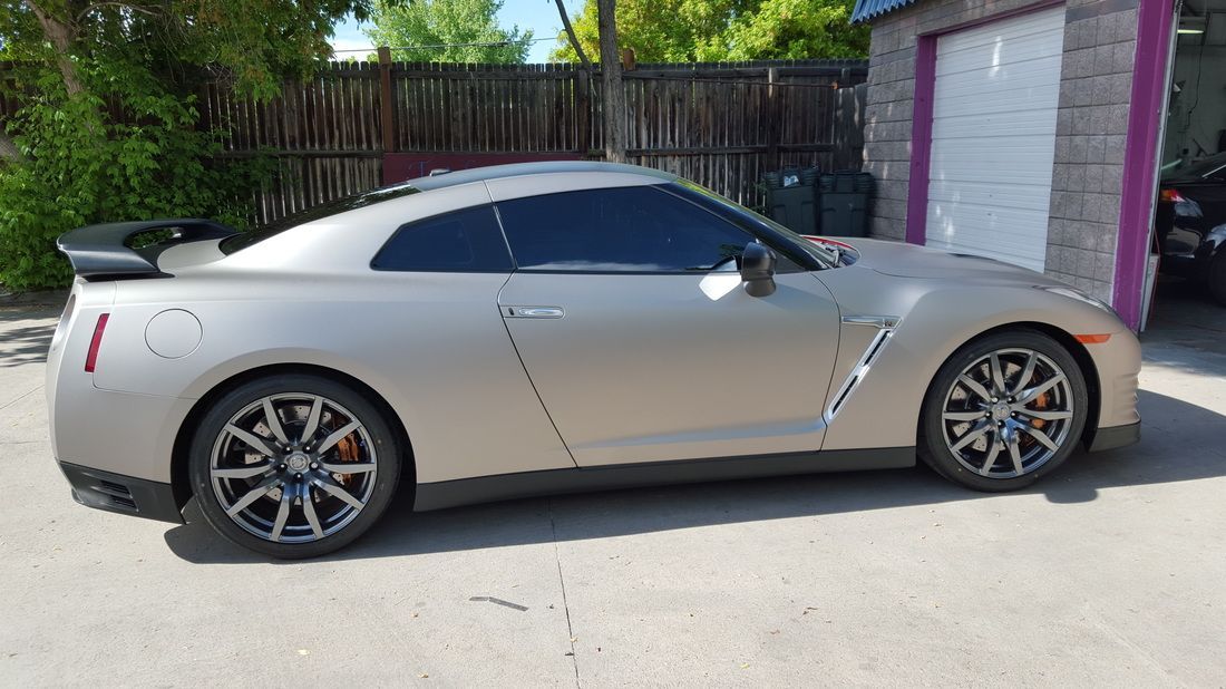 A silver sports car is parked in front of a garage.