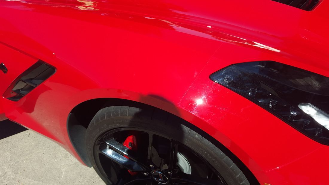 A red sports car with black wheels is parked on the side of the road.