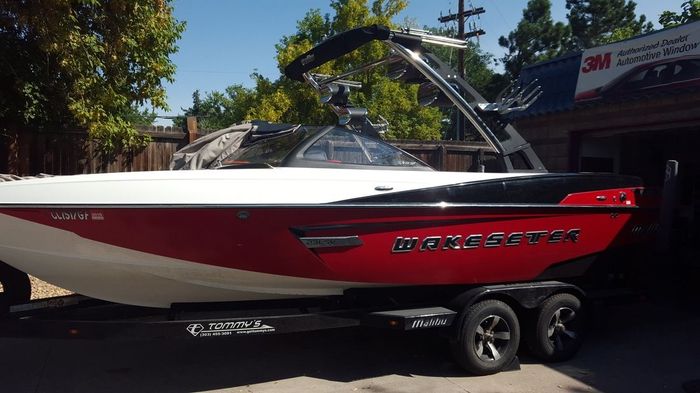 A red and white boat is parked in front of a 3m store