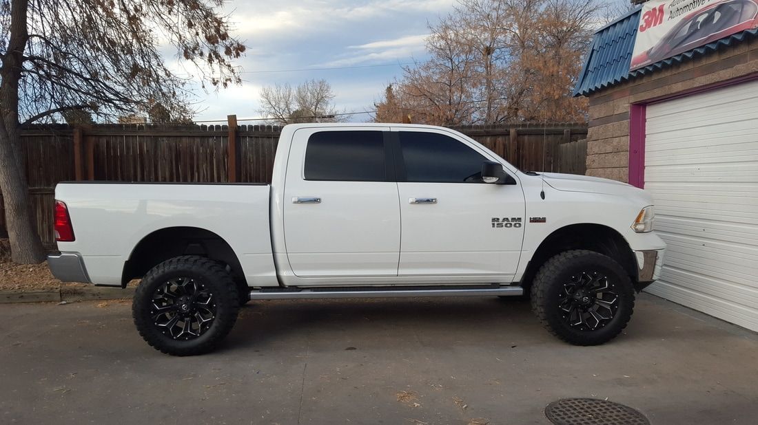 A white dodge ram truck is parked in front of a garage.