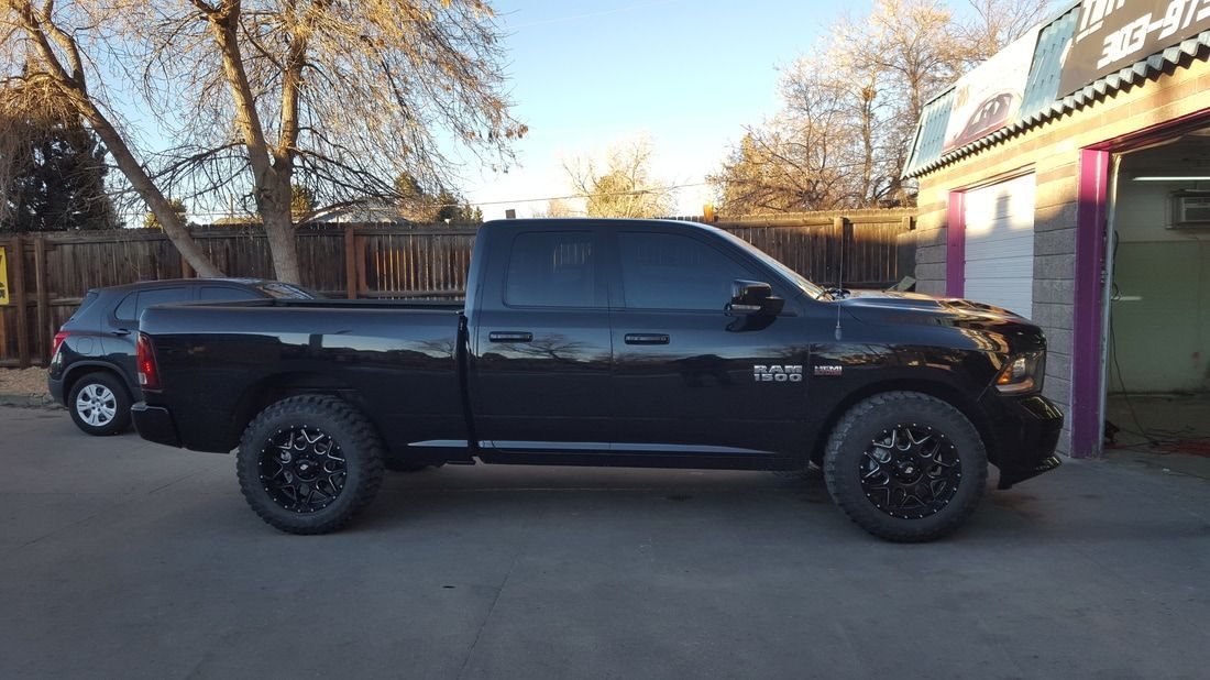 A black truck is parked in front of a garage.