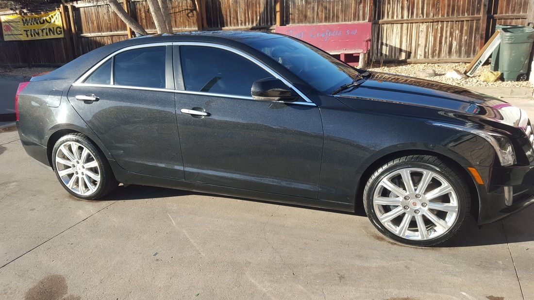 A black cadillac ats is parked in a parking lot.
