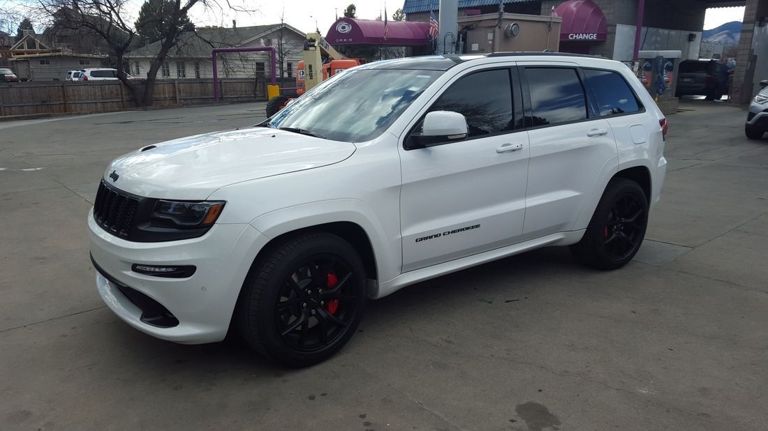 A white jeep grand cherokee is parked in a parking lot.