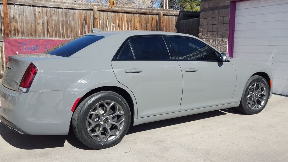 A gray car is parked in front of a garage.