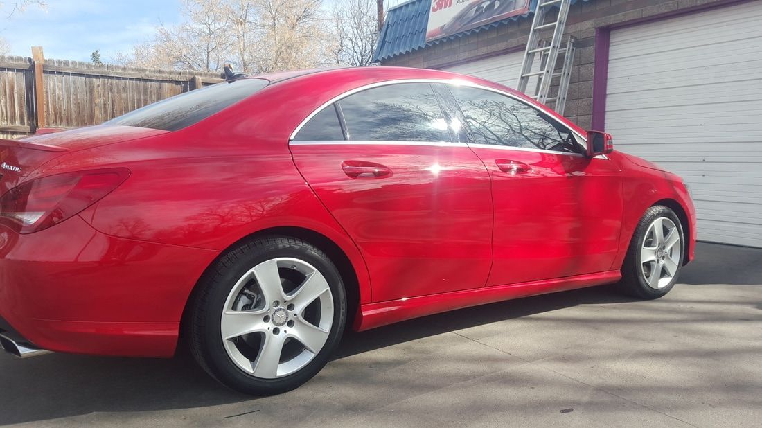 A red car is parked in front of a garage door.