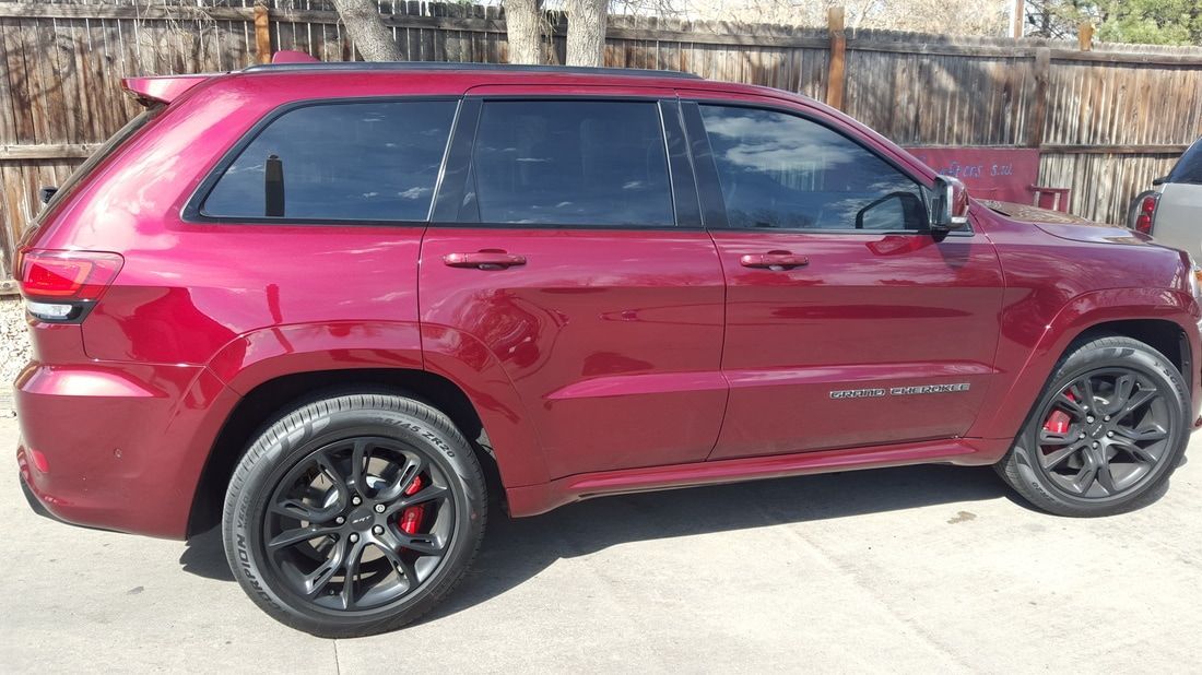 A red jeep grand cherokee is parked in a parking lot.