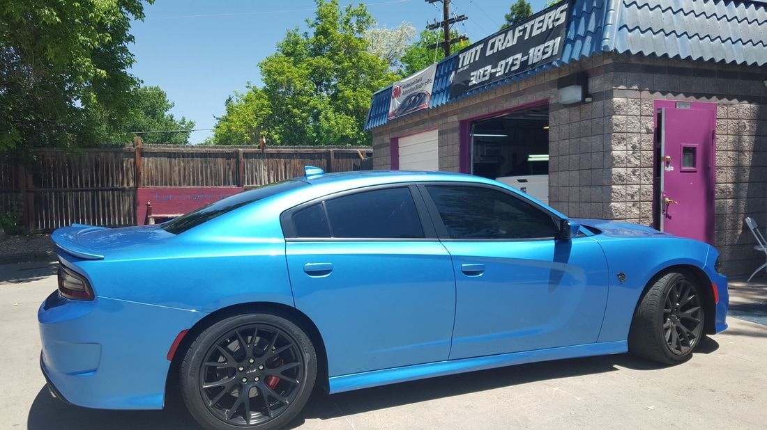 A blue dodge charger is parked in front of a building.