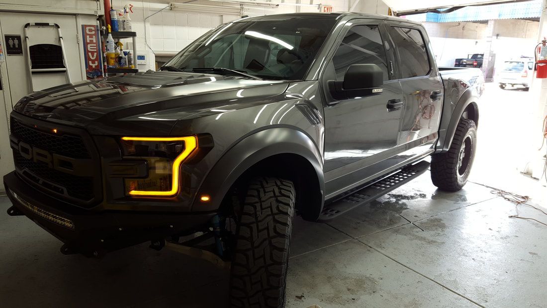 A gray ford raptor truck is parked in a garage.