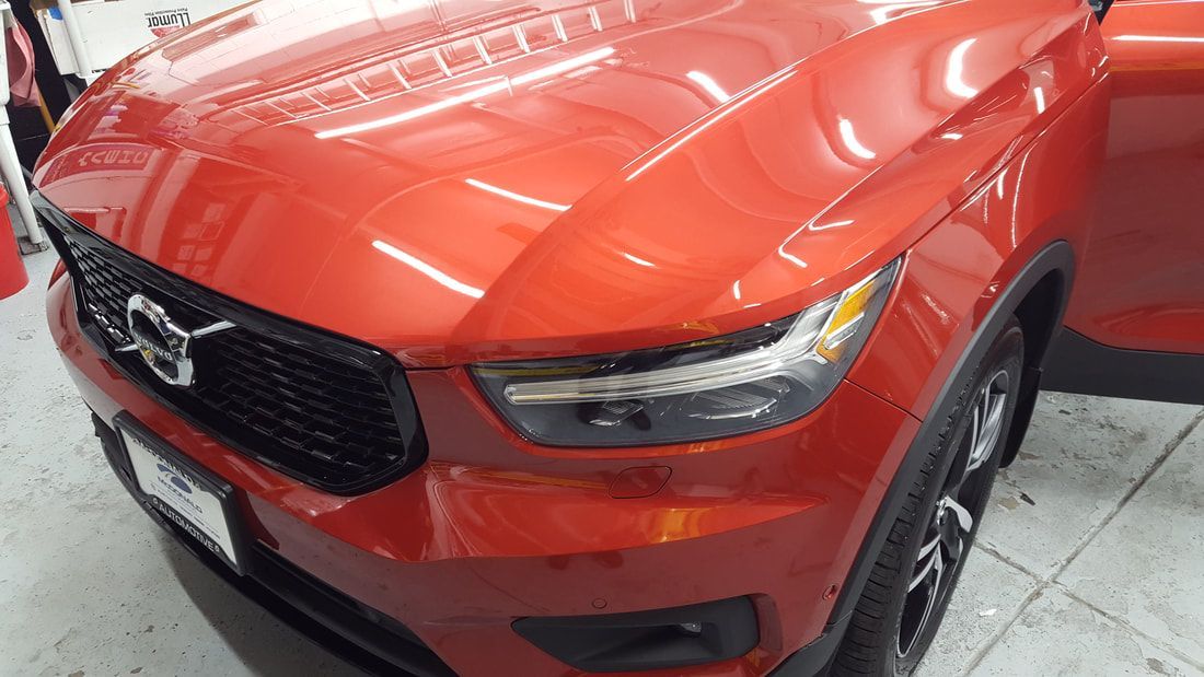 A red volvo xc40 is parked in a garage with its door open.