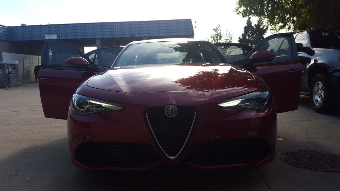A red car with its doors open is parked in front of a building.