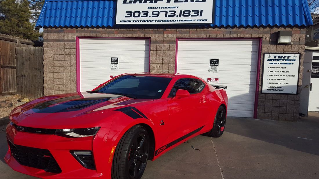A red car is parked in front of a garage.
