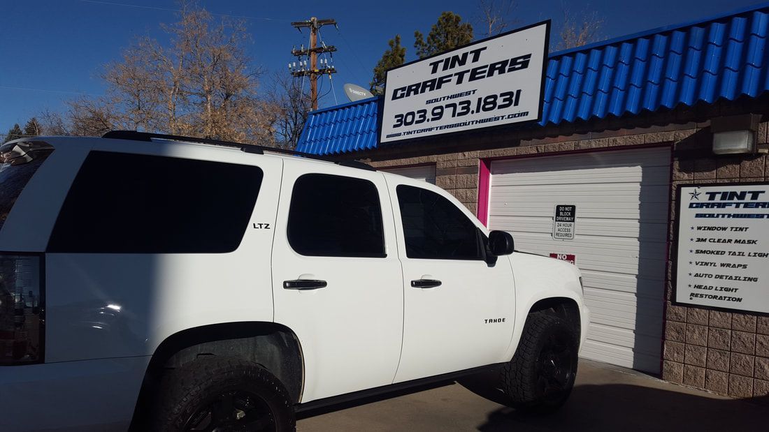 A white suv is parked in front of a building.