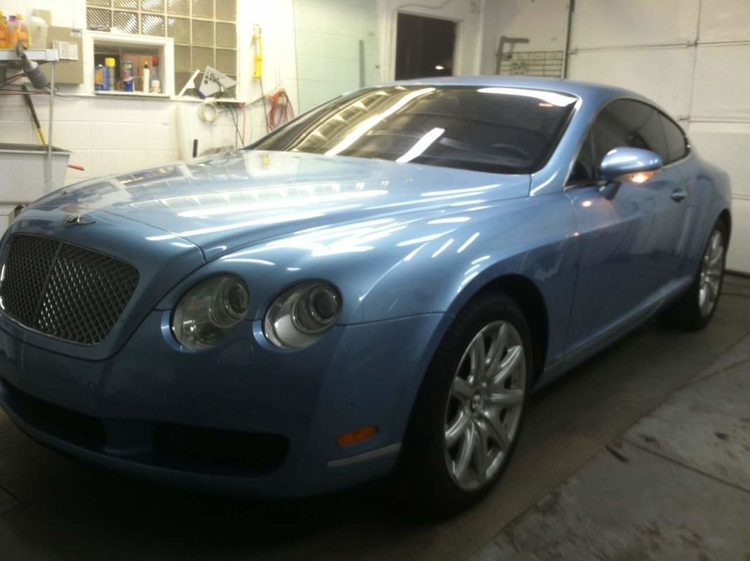A blue bentley is parked in a garage