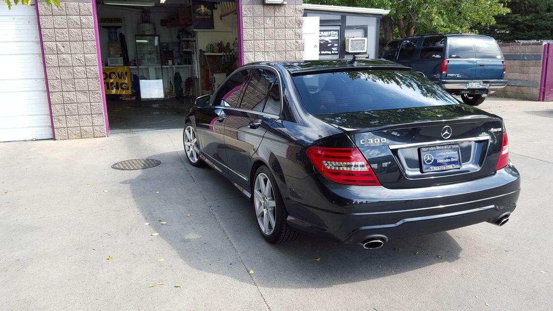 A black mercedes benz is parked in front of a garage.