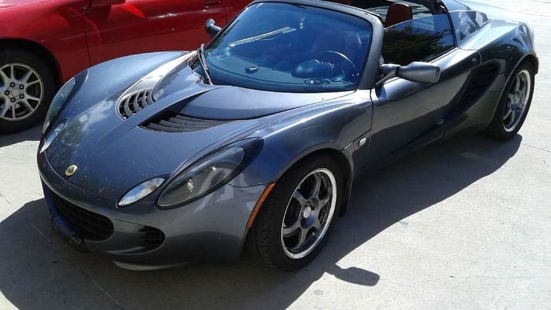 A gray sports car is parked next to a red car