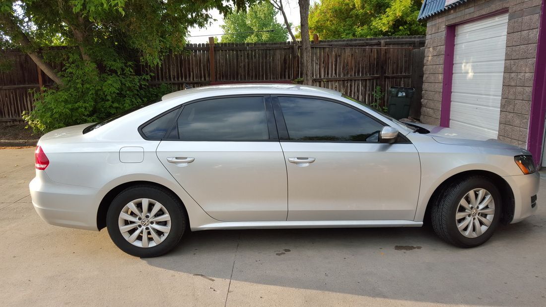 A silver volkswagen passat is parked in front of a garage.