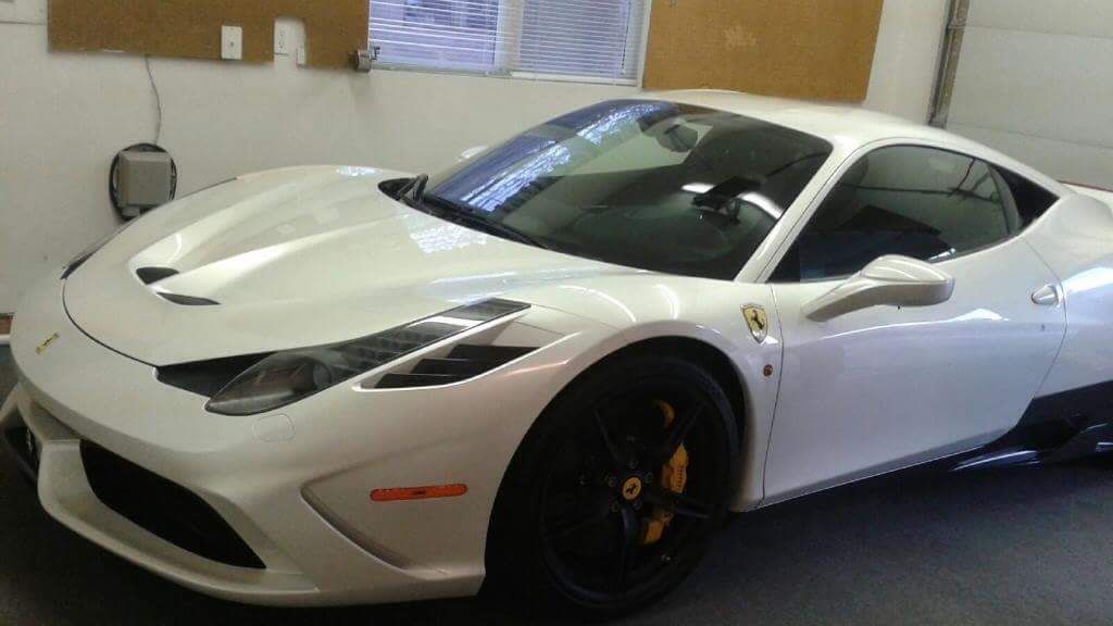 A white sports car is parked in a garage.