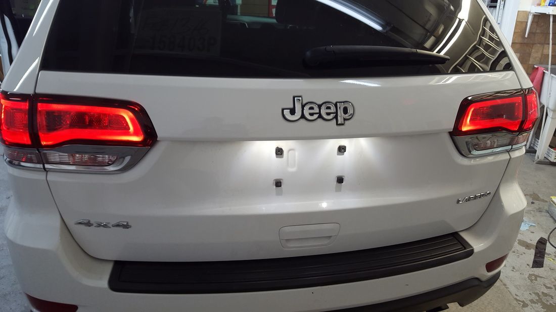A white jeep is parked in a garage