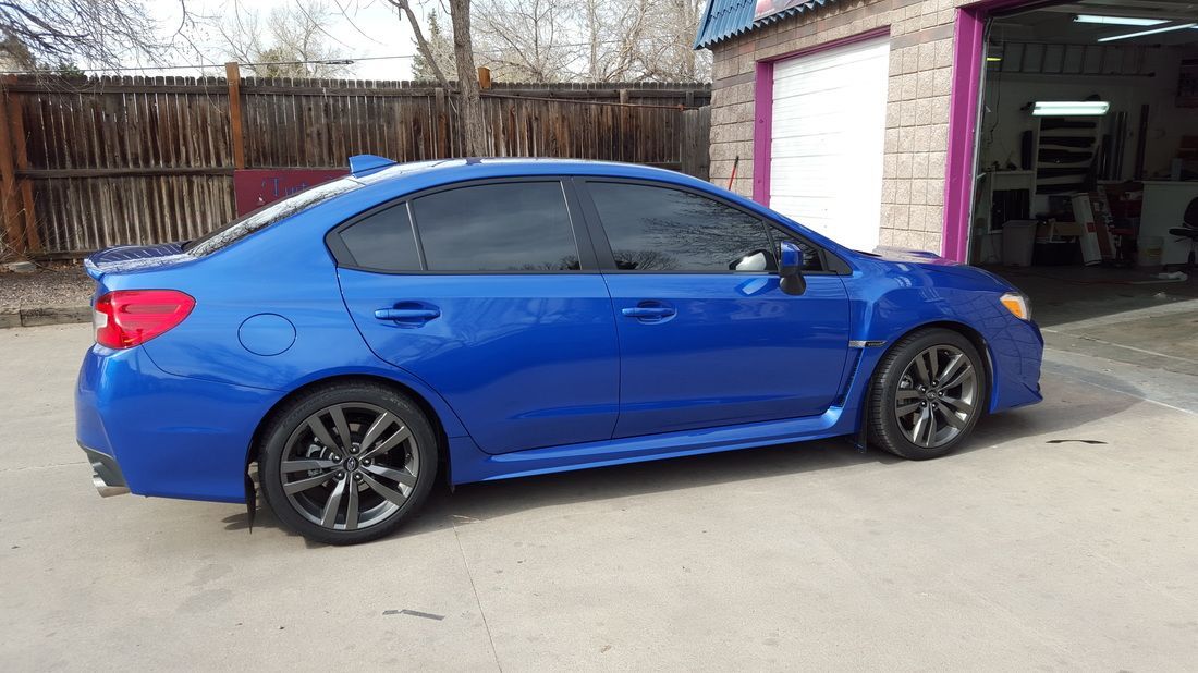 A blue subaru wrx sti is parked in front of a garage.