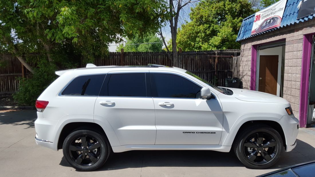 A white jeep grand cherokee is parked in front of a building.