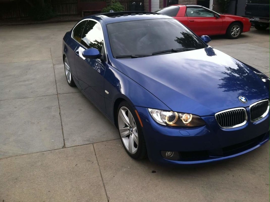 A blue bmw is parked next to a red corvette