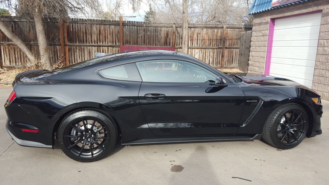 A black ford mustang is parked in front of a garage.